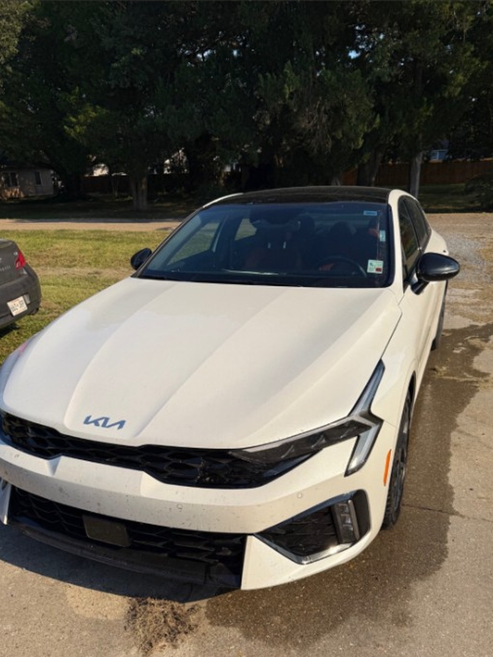 White Kia K5 exterior before detailing on a concrete driveway