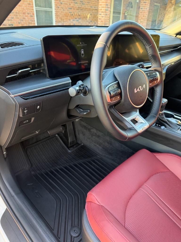 Kia K5 driver cabin with red leather seats and cleaned floor mats